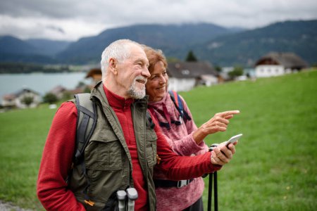 Foto de Pareja de ancianos activos caminando juntos en las montañas de otoño. Turistas mayores disfrutando de la naturaleza y el ejercicio. - Imagen libre de derechos