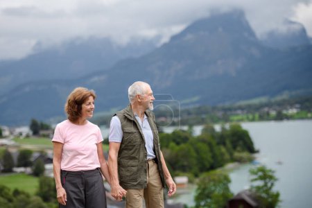 Téléchargez les photos : Couple âgé actif randonnée ensemble dans les montagnes du printemps. Touristes seniors appréciant la nature et l'exercice. - en image libre de droit