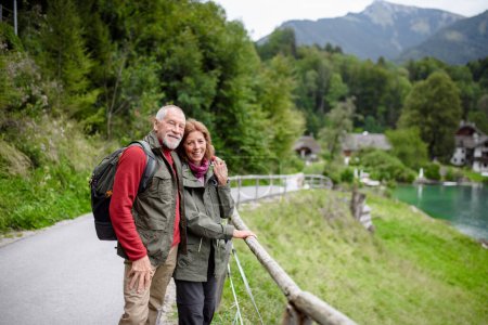Téléchargez les photos : Couple âgé actif randonnée ensemble dans les montagnes d'automne. Touristes seniors profitant d'une vue sur le lac. - en image libre de droit