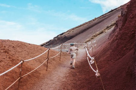 Foto de Chico corriendo por la colina. Familia explorando nuevos lugares durante las vacaciones de verano en las Islas Canarias, Lanzarote. - Imagen libre de derechos