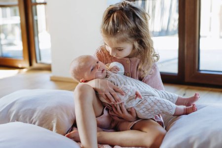 Photo for Portrait of big sister holding newborn sister. Girl carefully cuddling little baby. Sisterly love, joy for new family member. - Royalty Free Image