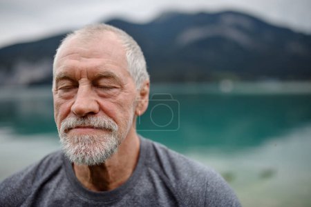Photo for Portrait of active senior man resting after hiking in mountains. Thoughtful elderly man enjoying peaceful untouched nature. - Royalty Free Image