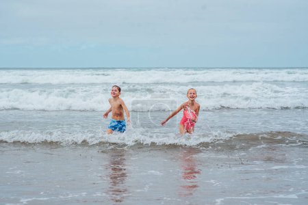 Téléchargez les photos : Frères et sœurs jouant sur la plage, courant, s'amusant. Fille et garçon sur la plage de sable des îles Canaries. Concept d'une plage familiale vacances d'été avec les enfants. - en image libre de droit