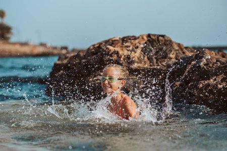 Photo for Young girl on the beach. Smilling blonde girl enjoying sandy beach, looking at crystalline sea in Canary Islands. Concept of beach summer vacation with kids. - Royalty Free Image