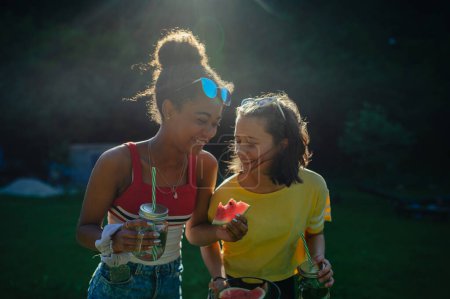 Téléchargez les photos : Joyeux jeunes filles adolescentes amis en plein air dans le jardin, manger de la pastèque. - en image libre de droit