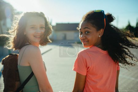 Téléchargez les photos : Vue arrière d'adolescentes amies avec des planches à roulettes marchant à l'extérieur en ville. - en image libre de droit