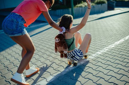Téléchargez les photos : Jeune adolescente meilleures amies avec des planches à roulettes passer du temps en ville pendant la chaude journée de vacances d'été. Patinage, s'amuser. - en image libre de droit