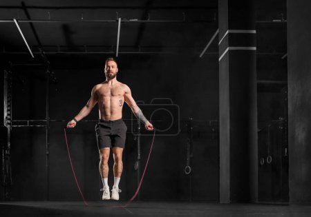 Photo for Handsome man jumping rope, doing double-unders as part of crossfit workout. Routine workout for physical and mental health. - Royalty Free Image