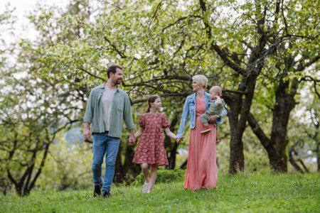 Photo for Family portrait with daughter and small toddler or baby, walking outdoors in spring nature. Nuclear family. - Royalty Free Image