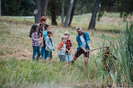 Photo for Teacher showing decaying water, lake plants to school children, during field teaching class. Outdoor active education helping young student to learn about ecosystem, nature. - Royalty Free Image