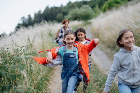 Junge Schüler amüsieren sich während des Biologieunterrichts und laufen den Feldweg hinunter. Engagierte Lehrer während des aktiven Unterrichts im Freien über Ökosystem, Ökologie und Natur.