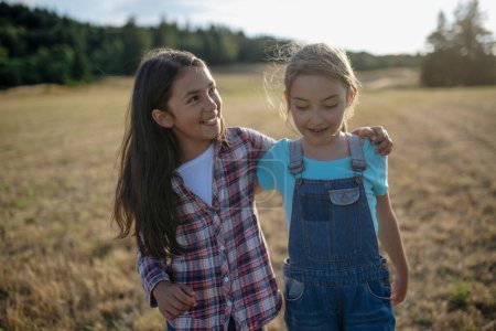 Cheerful young girl best friends spending time in nature, during sunset. Girls on walk, embracing.
