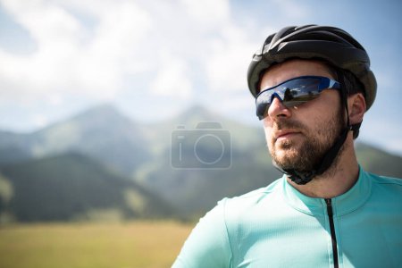 Téléchargez les photos : Portrait de cycliste masculin attrayant, à vélo à travers une belle nature, portant un casque et des lunettes de soleil. Concept de mode de vie sain. - en image libre de droit