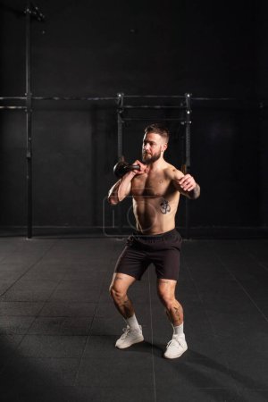 Man lifting a weight with hand, one arm dumbbell snatch, wearing only shorts, bare chest. Routine workout for physical and mental health.