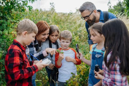 Photo for Young students learning about nature, forest ecosystem during biology field teaching class, observing wild plants. Dedicated teachers during outdoor active education. Teachers Day. - Royalty Free Image