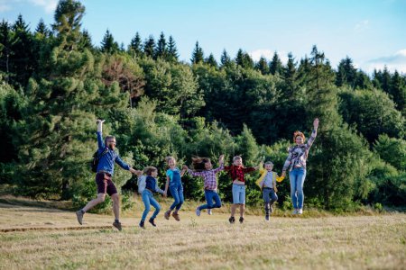 Photo for Young students walking across meadow during biology field teaching class, holding hands. Dedicated teachers during outdoor active education teaching about ecosystem and nature. - Royalty Free Image
