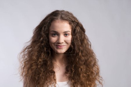 Photo for Portrait of a gorgeous teenage girl with curly hair. Studio shot, white background with copy space. - Royalty Free Image