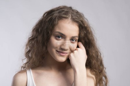 Foto de Retrato de una hermosa adolescente con el pelo rizado. Captura de estudio, fondo blanco con espacio de copia. - Imagen libre de derechos