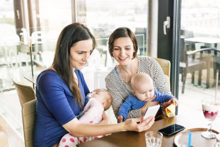 Neue Mutti-Freunde gehen mit Babys ins Café. Freizeit während des Mutterschaftsurlaubs gemeinsam in der Stadt verbringen.