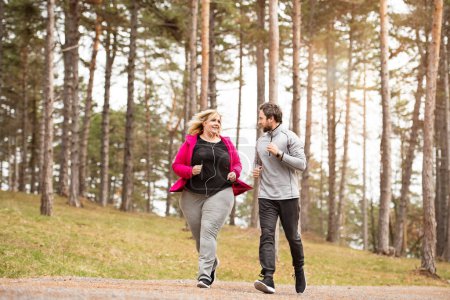 Eine übergewichtige Frau, die mit einem Freund in der Natur läuft. Bewegung im Freien für Menschen mit Fettleibigkeit, Unterstützung durch Freunde oder Fitnesstrainer.