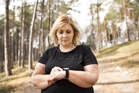 Eine übergewichtige Frau bereitet sich auf einen Lauf in der Natur vor. Bewegung im Freien für fettleibige Menschen.