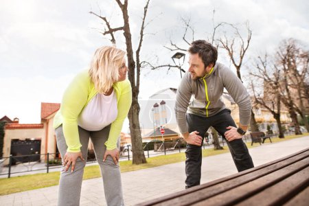 Une femme en surpoids qui court en ville avec un ami. Exercice en plein air pour les personnes obèses, soutien d'un ami ou d'un entraîneur de conditionnement physique.