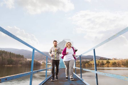 Téléchargez les photos : An overweight woman running in nature with friend. Exercising outdoors for people with obesity, support from friend or fitness coach. - en image libre de droit