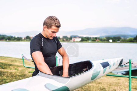 Young canoeist preparing canoe and paddle, going on water. Concept of canoeing as dynamic and adventurous sport