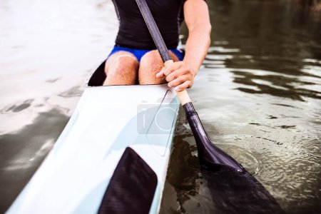 Gros plan du canoéiste assis en canot tenant la pagaie, dans l'eau. Concept du canoë-kayak comme sport dynamique et aventureux
