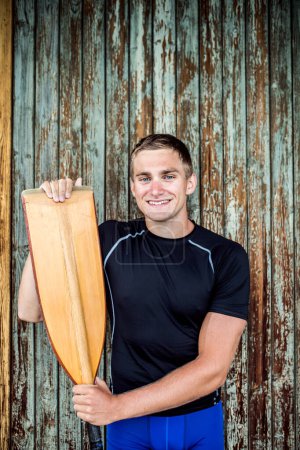 Portrat of young canoeist holding paddle. Concept of canoeing as dynamic and adventurous sport