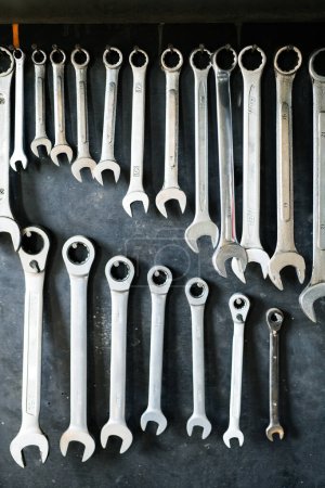 Photo for Combination wrenches set in auto repair shop. Mechanics repairing, maintaining car in garage. Black background. - Royalty Free Image
