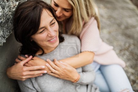 Adult daughter spending time with her mother outdoors. Beautiful daughter holding each other lovingly, hugging. Unconditional, deep maternal love, Mothers Day concept.