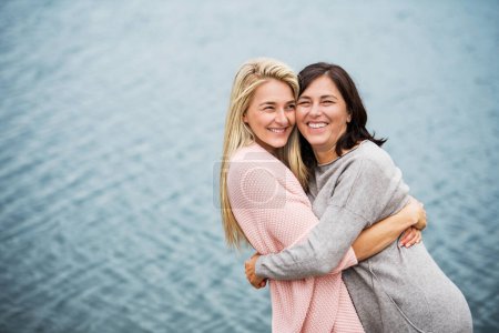 Mom and daughter on spring vacation together by lake. Unconditional, deep maternal love, Mothers Day concept.