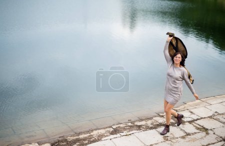 Photo for Portrait of beautiful mature woman with on vacation by lake. Hands in the air, happiness. - Royalty Free Image