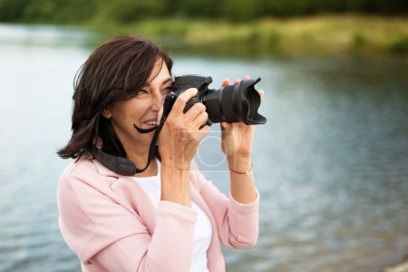 Téléchargez les photos : Portrait de belle femme mûre en vacances. Prendre des photos avec un appareil photo professionnel, capturer la beauté dans la nature autour d'elle. - en image libre de droit