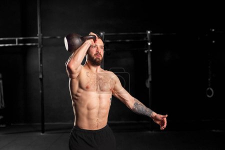 Man lifting kettlebell weight with hand, one arm dumbbell snatch, wearing only shorts, bare chest. Routine workout for physical and mental health.