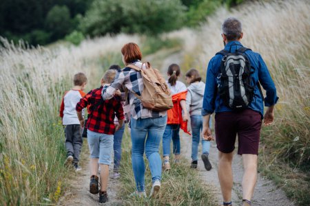 Photo for Rear view students during biology field teaching class, walking down the dirt path. Dedicated teachers during outdoor active education teaching about ecosystem, ecology and nature. - Royalty Free Image