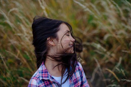 Photo for Portrait of beautiful young girl standing in nature, in the middle of tall grass with closed eyes, headshot. Copy space. - Royalty Free Image