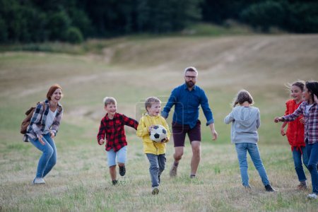 Photo for Young students playing with teacher outdoors, in nature, during field teaching class, running with ball, Dedicated teachers during outdoor active education.Teachers Day. - Royalty Free Image
