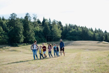 Photo for Young students walking across meadow during biology field teaching class, holding hands. Dedicated teachers during outdoor active education teaching about ecosystem and nature. - Royalty Free Image