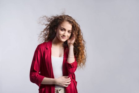 Téléchargez les photos : Portrait d'une magnifique adolescente aux cheveux bouclés. Plan studio, fond blanc avec espace de copie. - en image libre de droit