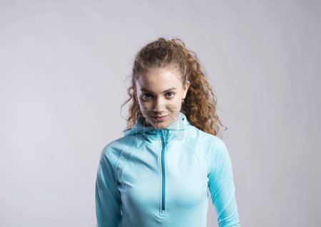 Photo for Portrait of a gorgeous fitness girl with curly hair, wearing workout clothes. Studio shot, white background with copy space. - Royalty Free Image