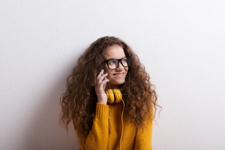 Foto de Retrato de una hermosa adolescente con el pelo rizado, haciendo una llamada telefónica. Captura de estudio, fondo blanco con espacio de copia. - Imagen libre de derechos