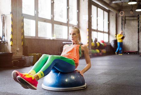 Foto de Hermosa mujer del deporte haciendo ejercicio en la pelota de equilibrio en el gimnasio. Entrenamiento de rutina para mujeres salud física y mental - Imagen libre de derechos