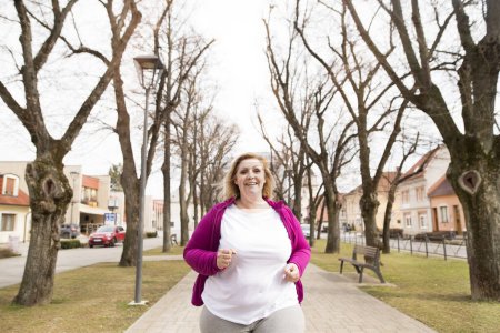 Übergewichtige Frau läuft im Stadtpark. Bewegung im Freien für fettleibige Menschen