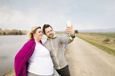 Zwei Freunde machen Selfie mit Smartphone beim Spaziergang in der Natur.
