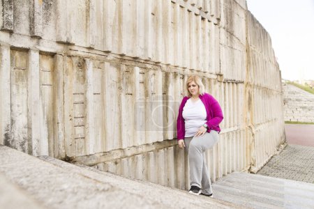 Übergewichtige Frau geht die Treppe im Stadtpark hinauf, die Treppe hinunter. Bewegung im Freien für fettleibige Menschen