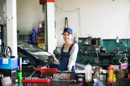 Téléchargez les photos : Mécanicien automobile femme réparation, entretien d'une voiture. Belle femme travaillant dans un garage, vêtue d'une combinaison bleue. Femme technicienne de service automobile. - en image libre de droit