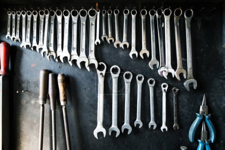 Photo for Combination wrenches set in auto repair shop. Mechanics repairing, maintaining car in garage. Black background. - Royalty Free Image