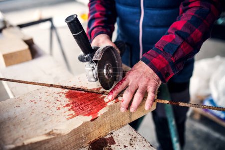 Sawing into finger with circular saw. Injured worker with bloody wound hand. Work injury, accident in workplace.